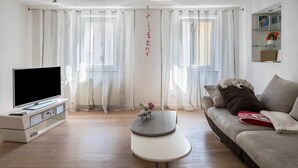 A living room with a flat-screen TV, a sofa, a coffee table, and a glass cabinet.