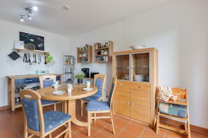 A dining area with a round table, chairs, and a cabinet with glass doors.