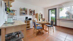 A compact kitchen with a dining area, equipped with basic amenities like a coffee maker and storage shelves. - Apartment 'Oreste' with Private Terrace, Private Garden and Wi-Fi (Overath)