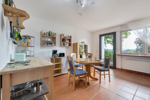 Cuina compacta amb zona de menjador, equipada amb els serveis bàsics com una cafetera i prestatges d'emmagatzematge.