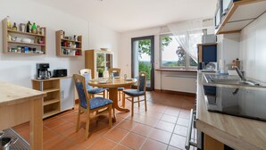 A compact kitchen with a dining area, a coffee machine, and a view through the window. - Apartment 'Oreste' with Private Terrace, Private Garden and Wi-Fi (Overath)