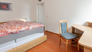 A bedroom with a bed, a chair, a desk, and a clock on the wall. - Apartment 'Oreste' with Private Terrace, Private Garden and Wi-Fi (Overath)