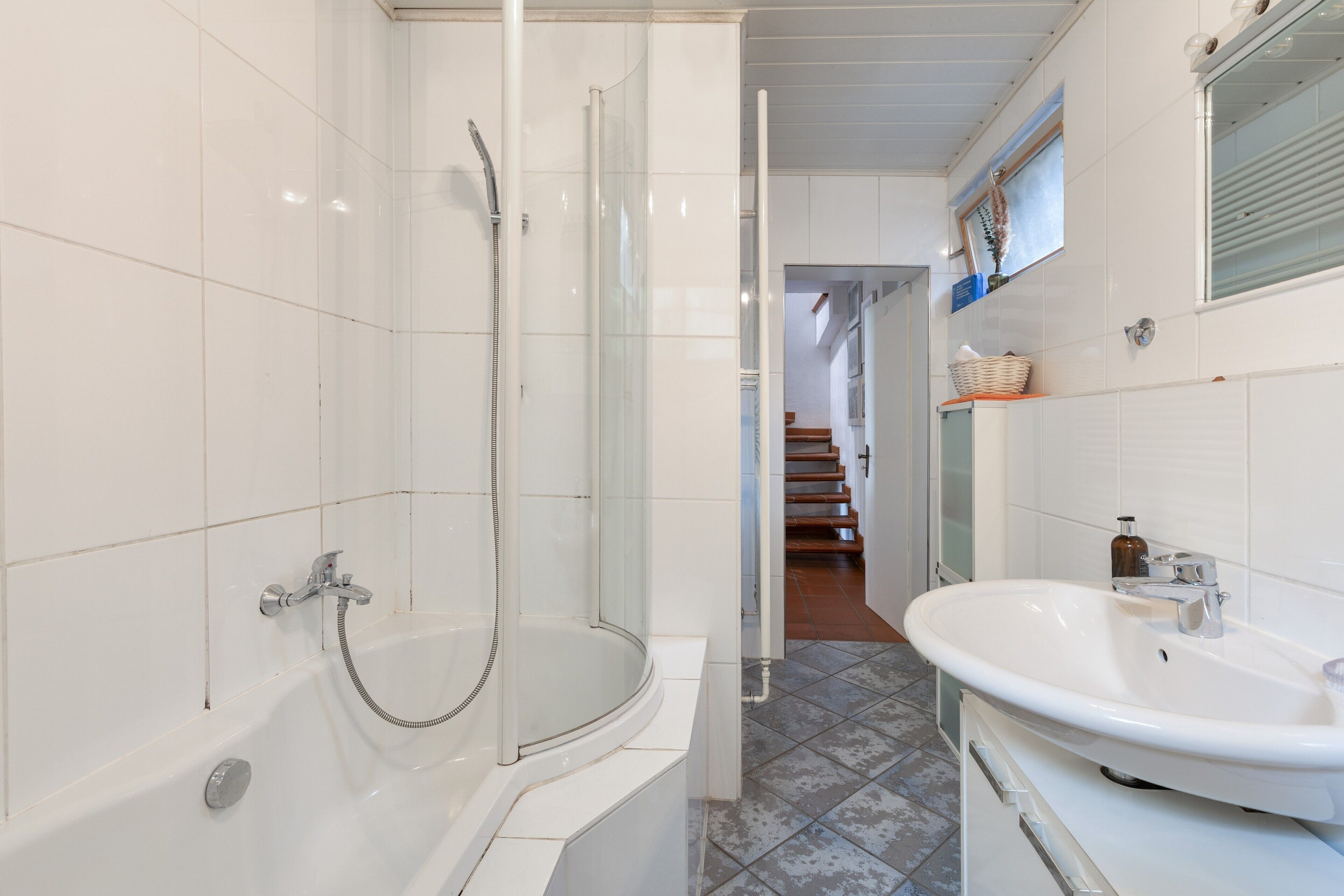 A modern bathroom with a bathtub, shower, and sink.