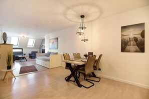 A modern living room with a dining area, a sofa, a coffee table, and a painting on the wall.