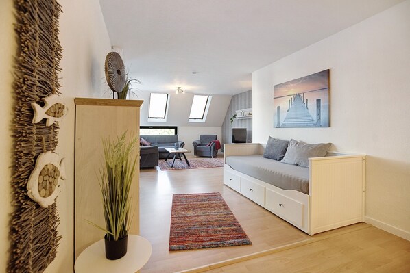 A modern living room with a sofa, a dining table, and a painting on the wall.