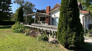 Ein Haus mit einer überdachten Veranda, einem Ziegelkamin und einem gepflegten Rasen.