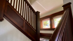 Eine Holztreppe mit weißen Wänden und einem Fenster oben.