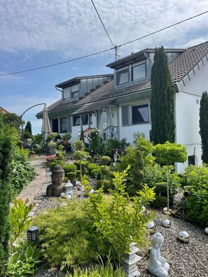 Un immeuble d’habitation doté d’un jardin, comprenant des statues et diverses plantes.