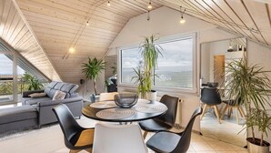 Ein modernes Interieur mit Essbereich, einer Couch und Topfpflanzen.