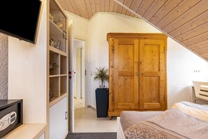 Une chambre avec une armoire en bois, un téléviseur fixé au mur et une plante en pot.