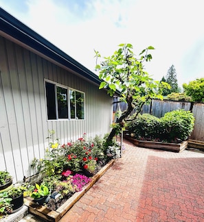 A residential property with a garden area, a wooden deck, and a house with a window. - Private guest room with separate washroom and entrance (West Vancouver)