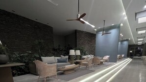 Eine moderne Lobby mit einem langen, beleuchteten Weg, Sitzbereichen und Deckenventilatoren.