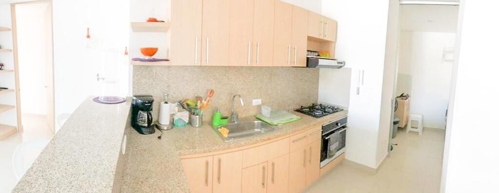 A compact kitchen with a granite countertop, a gas stove, a sink, and wooden cabinets.