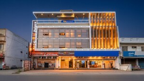 Een hotel met een moderne gevel, een duidelijke ingang en borden met 'Hotel OM Palace' en 'CICCI Bank'.