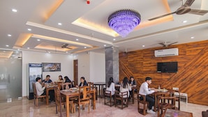A modern dining area with wooden walls, a chandelier, and ceiling fans. - Fabhotel Meridian Inn (Kharar)