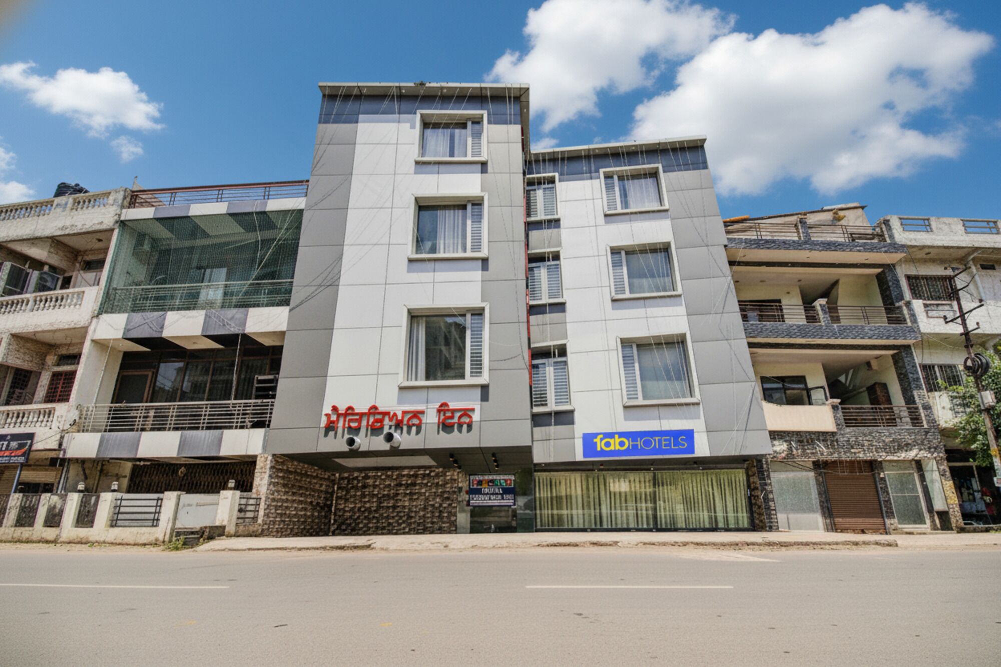 Ein mehrstöckiges Hotel mit moderner Fassade, das ein auffälliges Schild mit roter und weißer Schrift trägt.