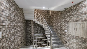 A staircase with a metal railing leading to a landing, surrounded by brick walls. - Fabhotel Meridian Inn (Kharar)
