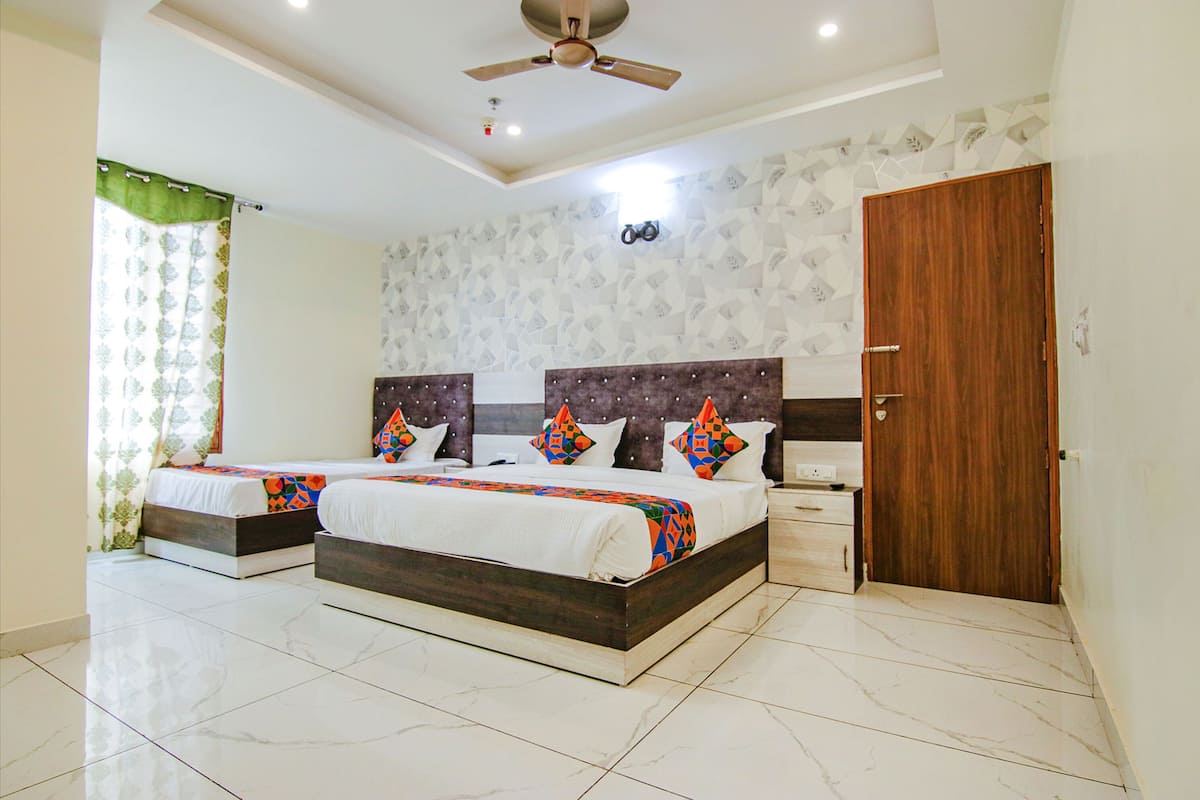 A bedroom with two beds, a wooden door, and a ceiling fan.