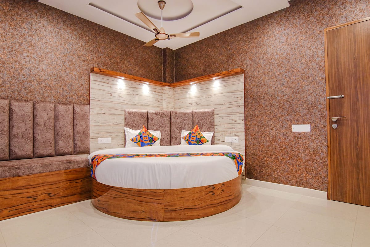 A bedroom with a curved bed, a wooden headboard, and a ceiling fan.