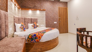 A bedroom with a bed, a wooden headboard, a ceiling fan, and a wooden door. - Fabhotel Meridian Inn (Kharar)