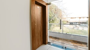 Quarto moderno com porta de madeira, varanda de vidro e vista para um estacionamento.