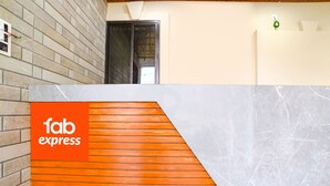Uma área de recepção com parede de tijolos, balcão de ripas de madeira e detalhes em mármore.