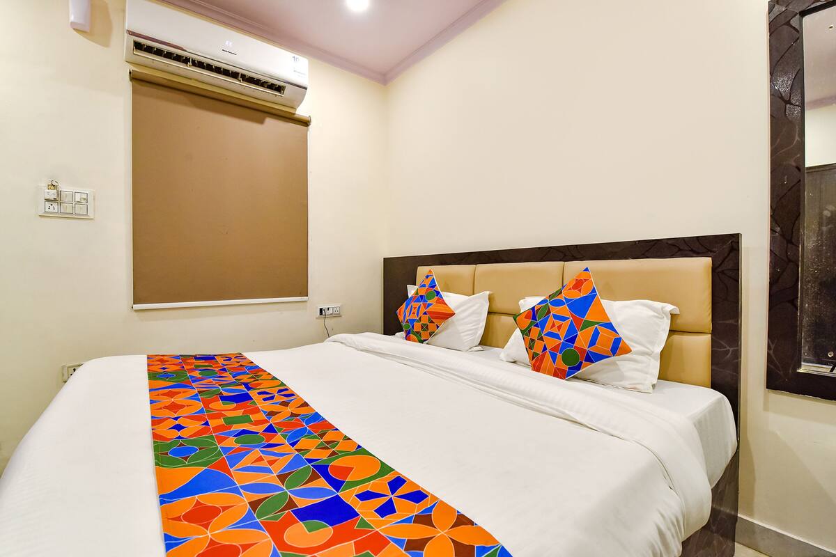 Une chambre d’hôtel équipée d’un lit, d’un appareil de climatisation et d’une fenêtre avec des stores.