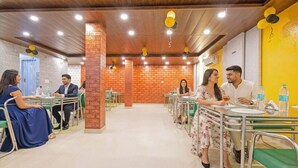 Un comedor con mesas y sillas, paredes de ladrillo y techo de madera.