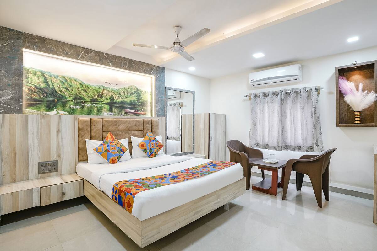 A modern bedroom with a bed, bedside table, chair, and a desk with a chair.