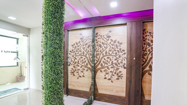 Un espace d’accueil doté d’une porte en verre, d’un mur en bois orné d’un motif d’arbre et d’un jardin vertical.