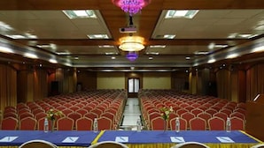 A conference room with rows of red chairs, a long table with a blue tablecloth, and a chandelier. - Fabhotel Prime Chennai Deluxe (Chennai)