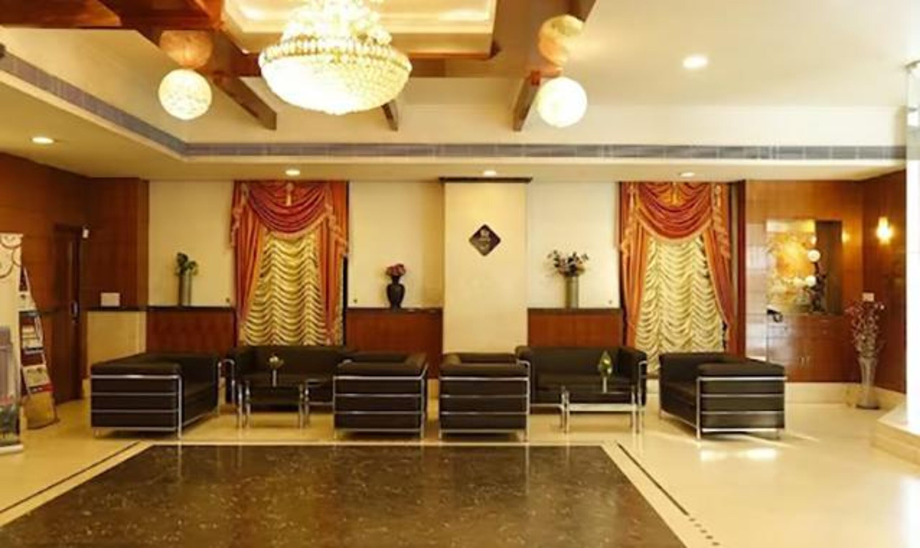 A hotel lobby with a marble reception desk, black seating, and a chandelier.