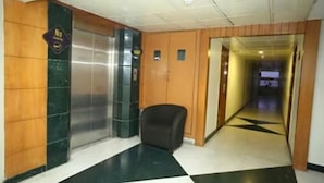 A hotel lobby with a checkered floor, a black office chair, and an elevator. - Fabhotel Prime Chennai Deluxe (Chennai)