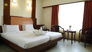 A hotel room with a large bed, two bedside tables, a chair, and a small table with a vase. - Fabhotel Prime Chennai Deluxe (Chennai)