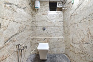 A bathroom with a marble wall, a toilet, a shower, and a hand dryer. - Fabhotel Max Inn (Ahmedabad)