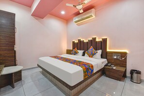A modern hotel room with a large bed, a desk, and a ceiling fan. - Fabhotel Max Inn (Ahmedabad)