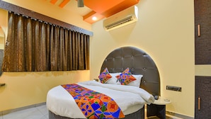 A modern bedroom with a round bed, a headboard, a bedside table, and a nightstand. - Fabhotel Max Inn (Ahmedabad)