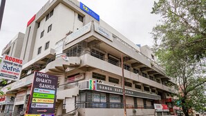 A multi-story hotel with a signboard indicating amenities like WiFi, 24-hour hot water, and intercom services. - Fabhotel Bhakti Sankul (Nashik)