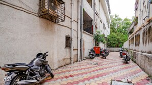 A narrow alley with tiled pavement, parked motorcycles, and buildings with barred windows and balconies. - Fabhotel Bhakti Sankul (Nashik)