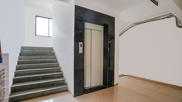 A staircase leading to an elevator in a clean, modern interior with white walls and a tiled floor. - Fabhotel Bhakti Sankul (Nashik)