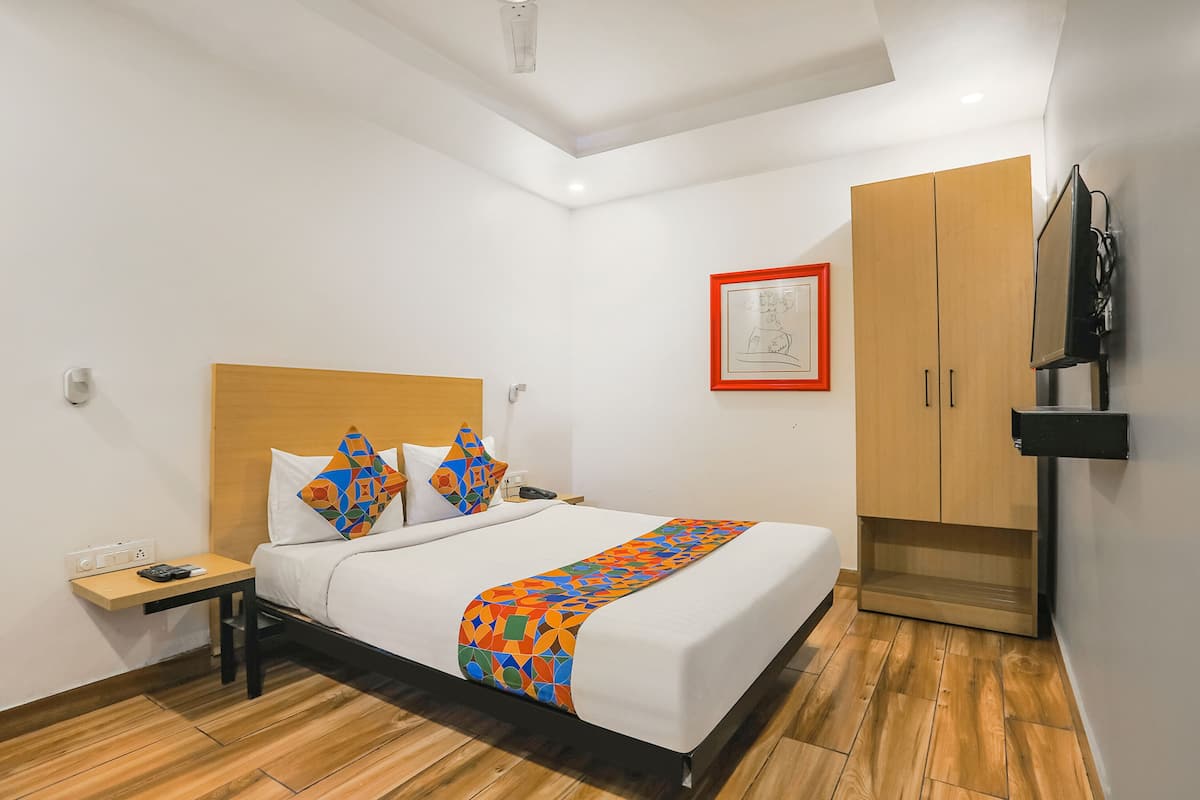 Una habitación de hotel con cama, mesita de noche, televisión y armario.