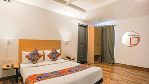 A hotel room with a bed, a nightstand, a bedside table, a ceiling fan, a door, and a mirror on the wall. - FabHotel PP Residency (New Delhi)