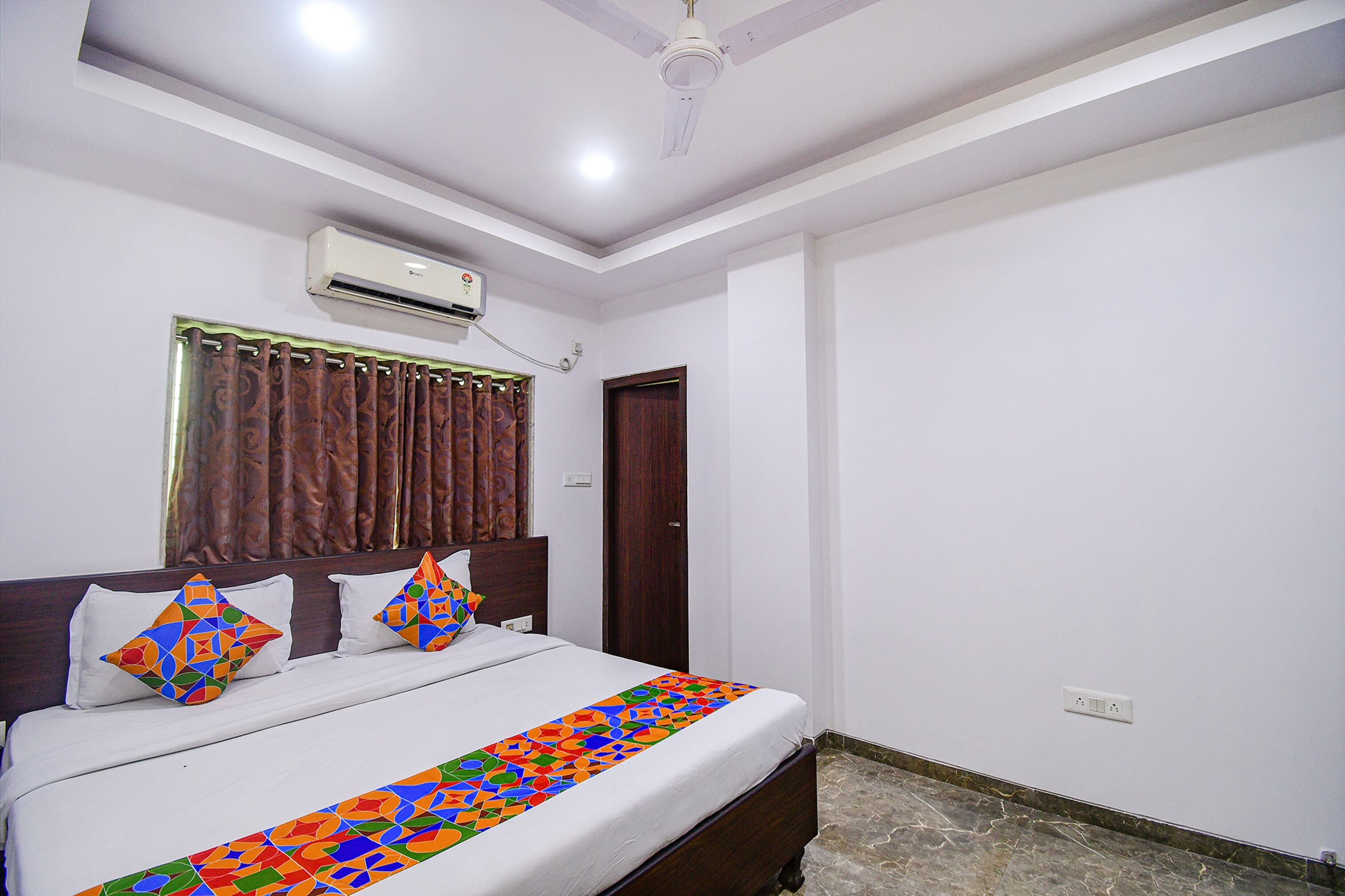 A bedroom with a bed, curtains, an air conditioning unit, and a door.