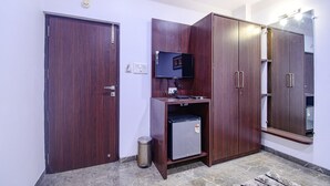 A room with a closed door, a small refrigerator, a television on a stand, and a mirror on the wall. - Fabhotel Rani Tower (Barasat)