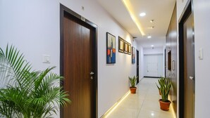 A hallway with a wooden door labeled 507, potted plants, and framed artwork on the walls. - Fabhotel Rani Tower (Barasat)