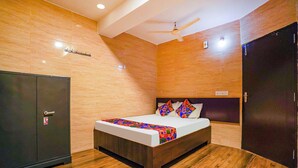 Un dormitorio con cama, piso de madera, ventilador de techo y armario.