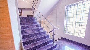 Una escalera con barandillas metálicas y suelo de baldosas que conduce a una habitación con ventana.