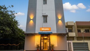 Um edifício alto e moderno com uma placa 'fabexpress' na entrada, apresentando uma fachada simples e um telhado plano.