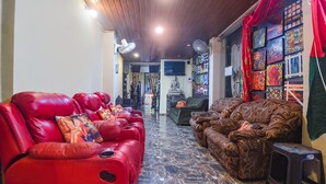 A spacious living area with a red sofa, a patterned sofa, and a television. - FabExpress Corinthia Boutique Rooms, Candolim Beach (Candolim)