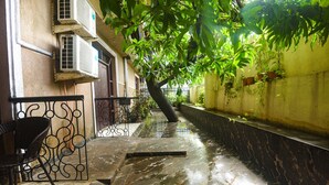 A narrow corridor with a marble floor, a metal railing, and potted plants. - FabExpress Corinthia Boutique Rooms, Candolim Beach (Candolim)